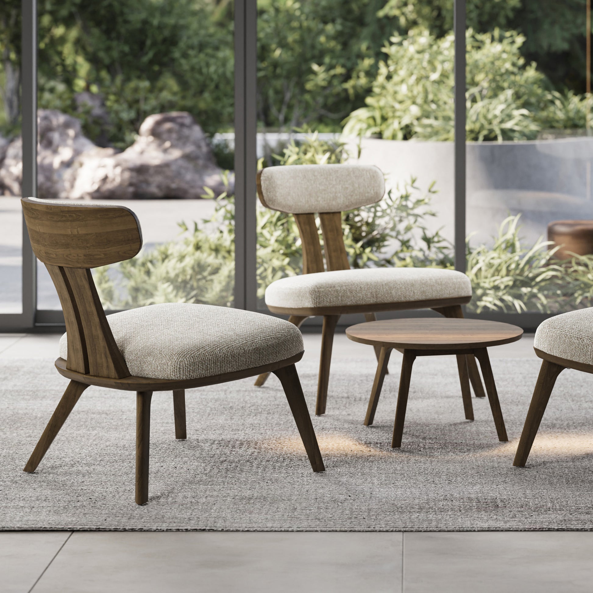 Estelle Walnut Lounge Chairs by Copeland Furniture with beige cushions next to a small round table.