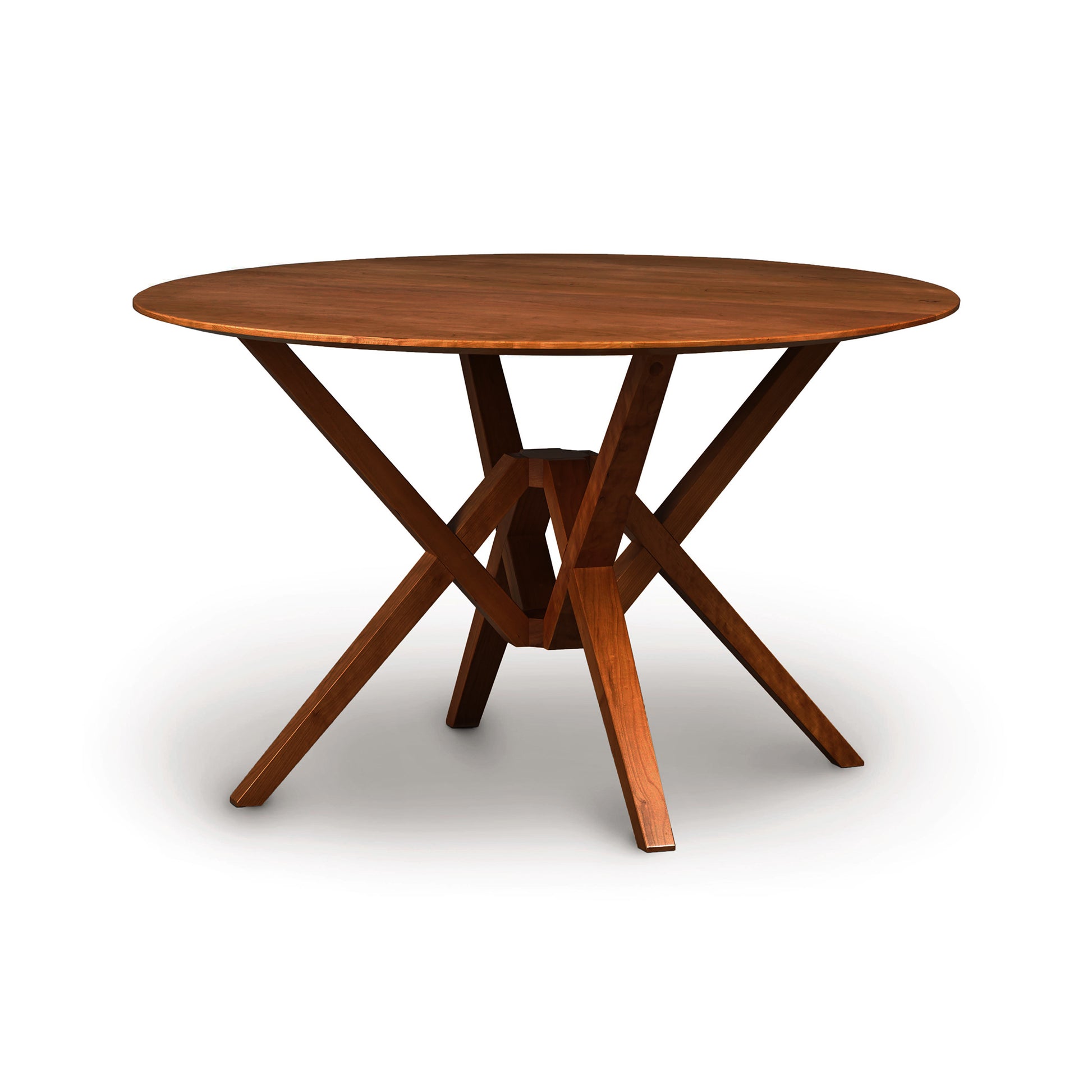 A round, Copeland Furniture Exeter Round Solid Top Dining Table made from sustainably harvested hardwoods with a crossed-leg support design, isolated on a white background.