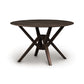 A round, dark wooden Copeland Furniture Exeter Round Solid Top Dining Table with a cross-leg design made from sustainably harvested hardwoods on a white background.