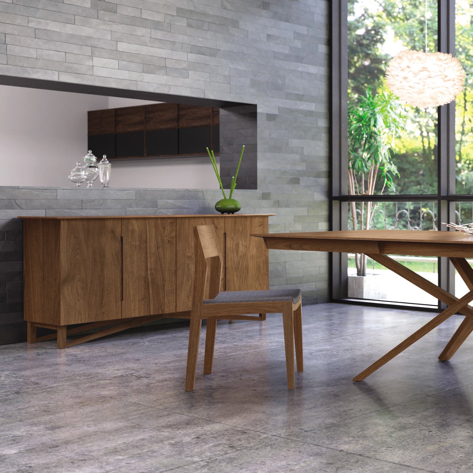 A modern dining room featuring a wooden table and matching wooden chairs on a stone tile floor. The room includes the Copeland Furniture Exeter Buffet for dining storage, a large window showcasing a view of greenery, and a decorative white pendant light. The walls are covered in grey tiles, perfectly complementing the natural hardwood elements.