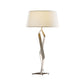 A modern facet table lamp with a twisted metallic base by Hubbardton Forge and a large, cylindrical white lampshade, against a white background.