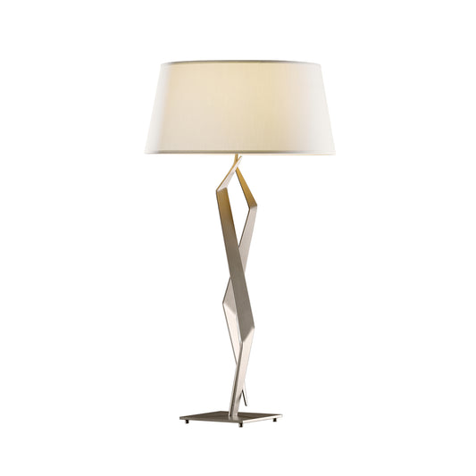 A Facet Table Lamp from Hubbardton Forge with a white shade.