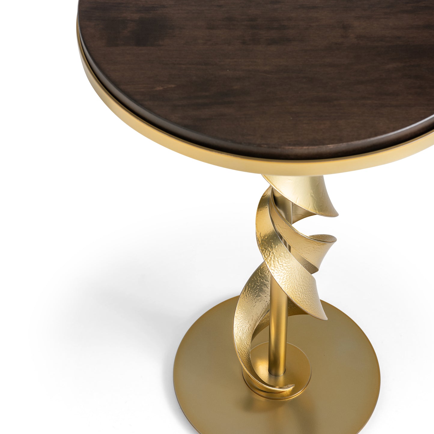 The Hubbardton Forge Folio Wood Top Accent Table boasts a sophisticated top made of dark Vermont Maple Wood, accompanied by a gold spiral metal pedestal. The pedestal is elegantly perched on a circular base with a modern brass finish, beautifully merging contemporary and elegant design elements.