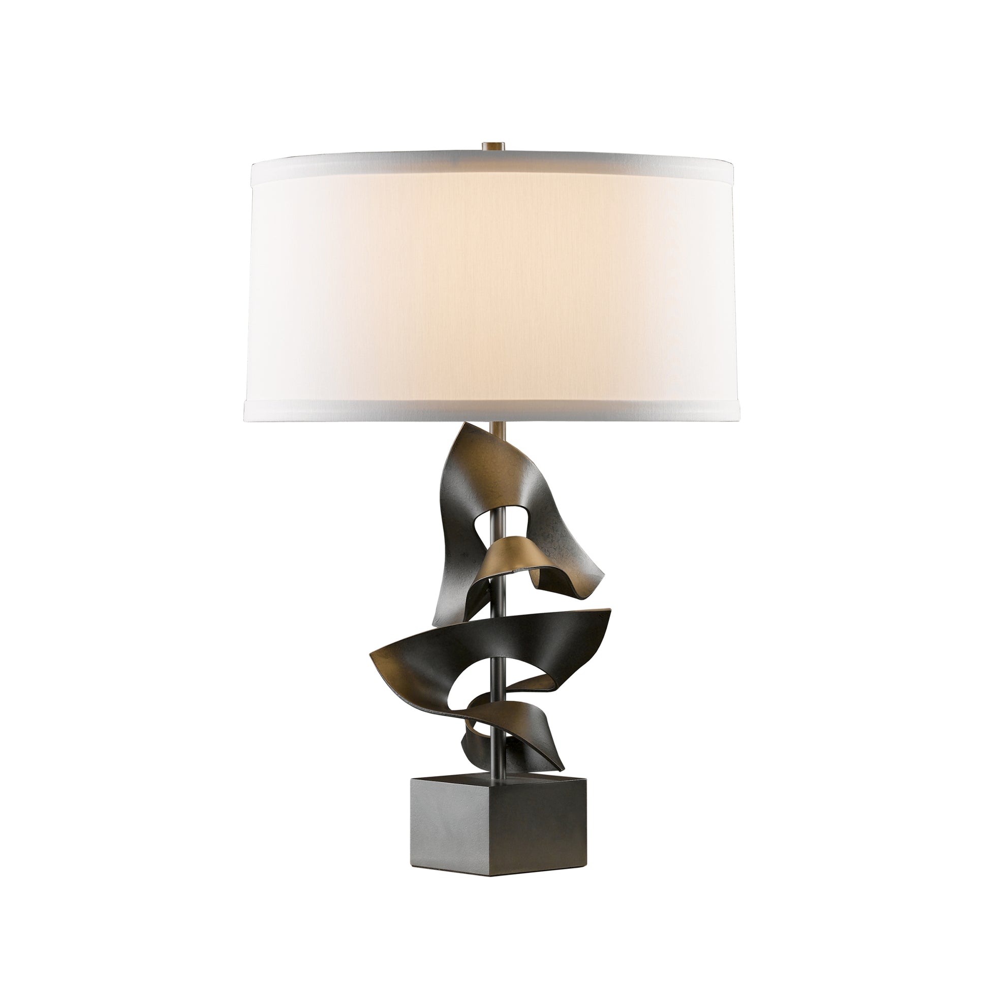 A modern Hubbardton Forge Gallery Two Fold Table Lamp with a sculptural, spiraling handcrafted metal base in a dark finish, supporting a horizontal, rectangular, off-white lampshade, isolated on a white background.
