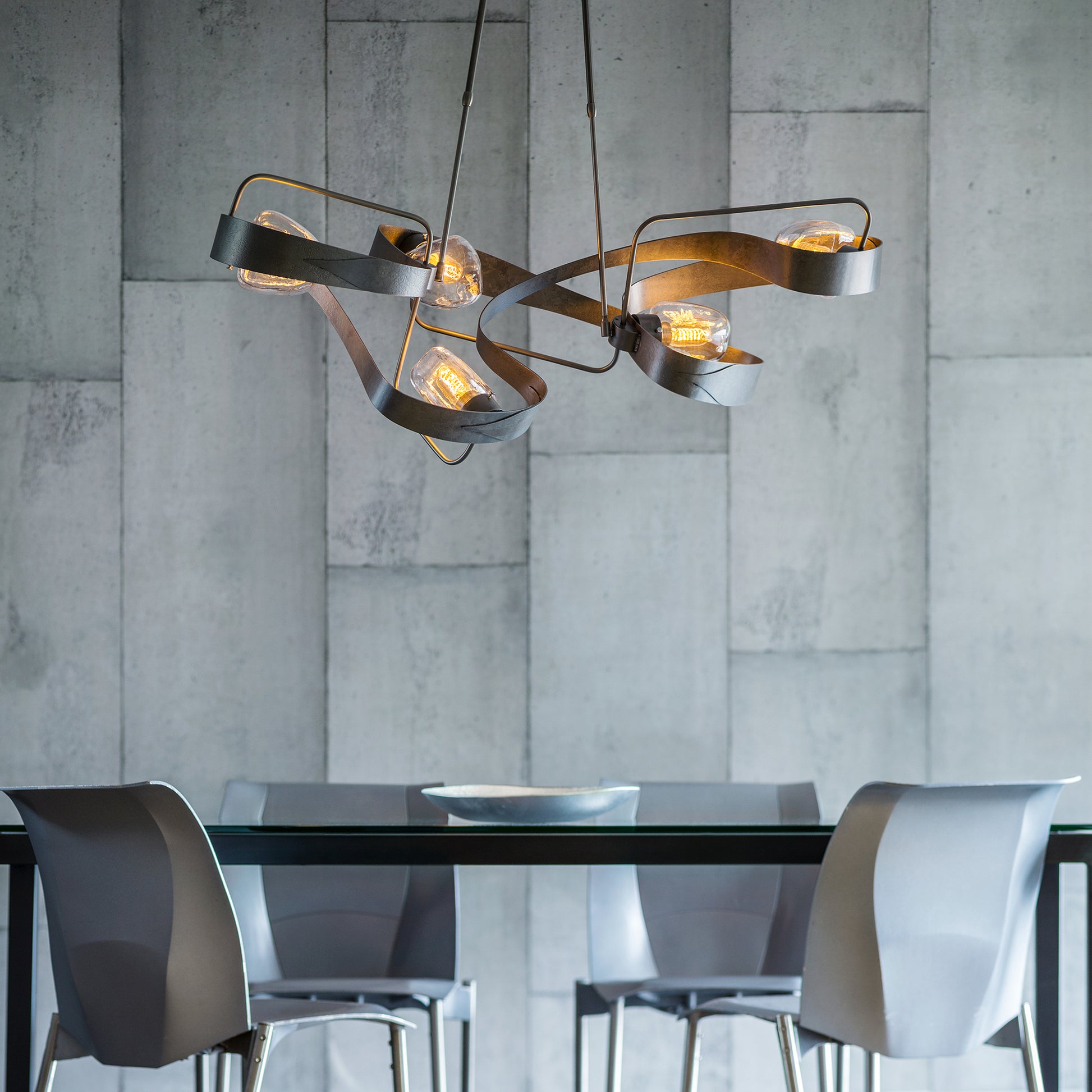 A modern dining room with Hubbardton Forge Graffiti Pendant lighting and grey chairs.