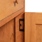 Corner of a solid wood cabinet with a visible metal hinge connecting two sections, featuring an eco-friendly oil finish typical of the Vermont Furniture Designs Heartwood Shaker 1-Drawer Nightstand with Door.
