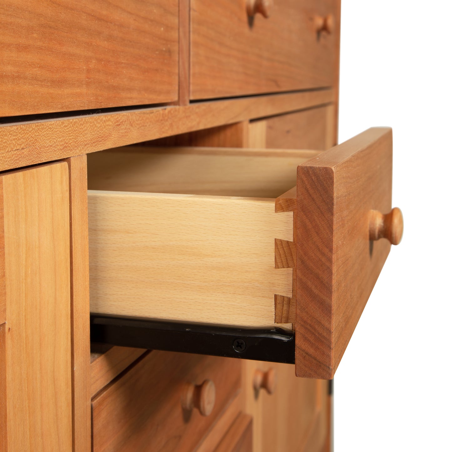 An open wooden drawer from a Vermont Furniture Designs Heartwood Shaker Sideboard showcasing dovetail joint construction and a black metal slide mechanism, set against a white background.