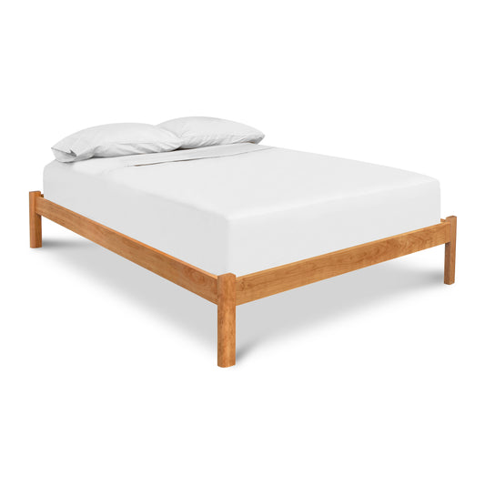A Vermont Furniture Designs Heartwood Shaker Studio-Style Platform Bed with a white mattress and two pillows on an isolated white background.