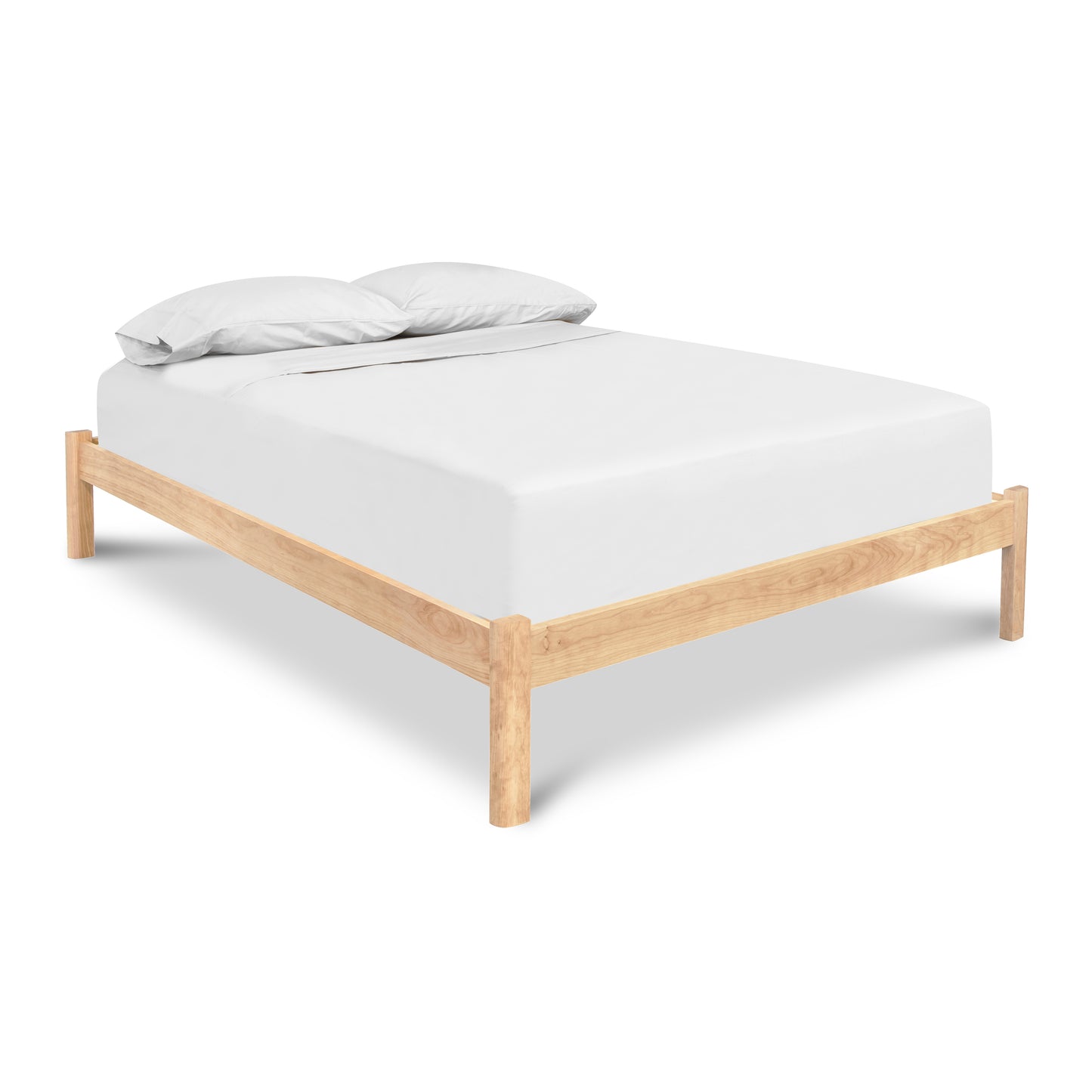 Heartwood Shaker Studio-Style Platform Bed in cherry wood with a white mattress and two pillows by Vermont Furniture Designs.