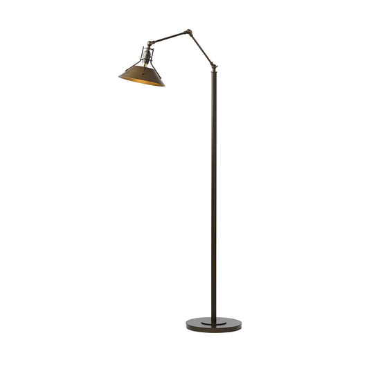 The Hubbardton Forge Henry Floor Lamp features an industrial design, with a metal shade that beautifully contrasts against the white background.