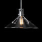 A Hubbardton Forge Henry Medium Glass Shade Pendant with a black background featuring a glass shade and modern industrial styling.