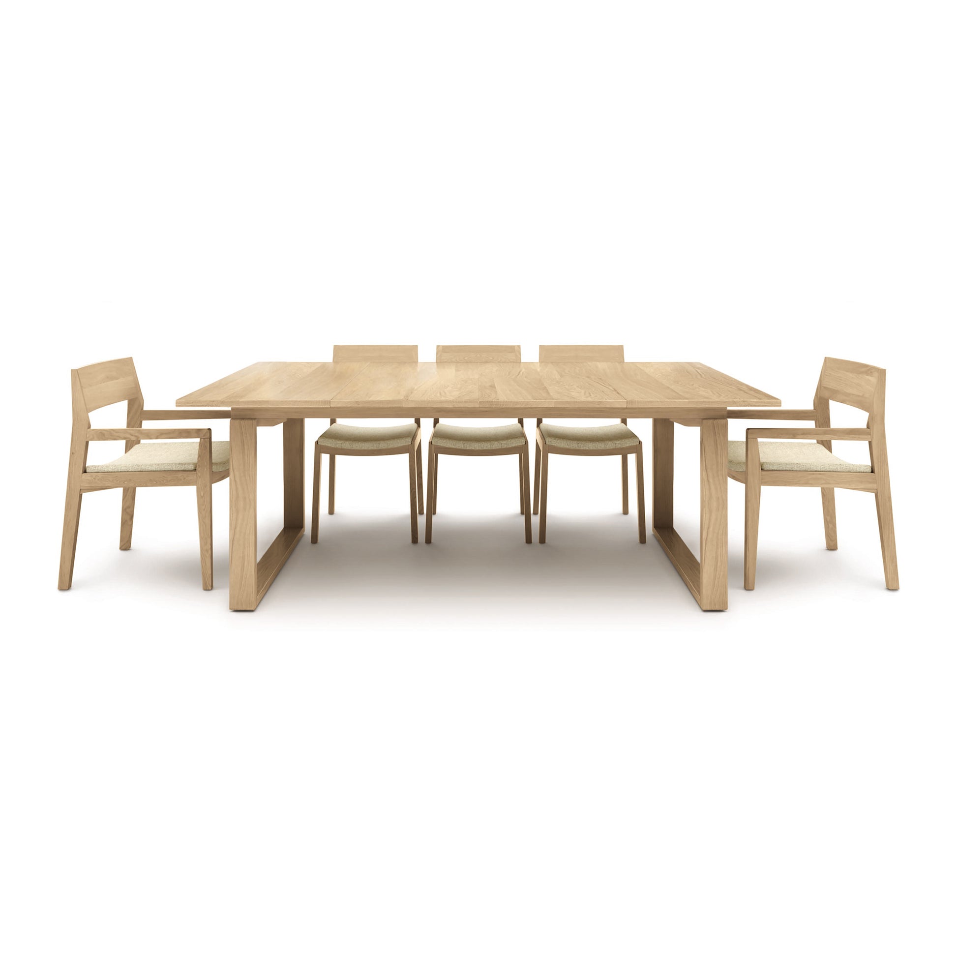 A white background showcases the Copeland Furniture Iso Oak Extension Dining Table, accompanied by six chairs. Made with solid oak wood, this dining set exudes elegance and durability.
