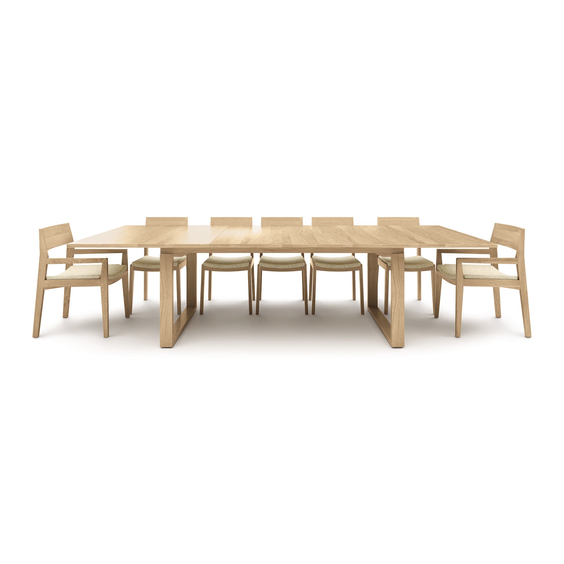 A Copeland Furniture Iso Extension Dining Table made from solid oak wood with six chairs on a white background.