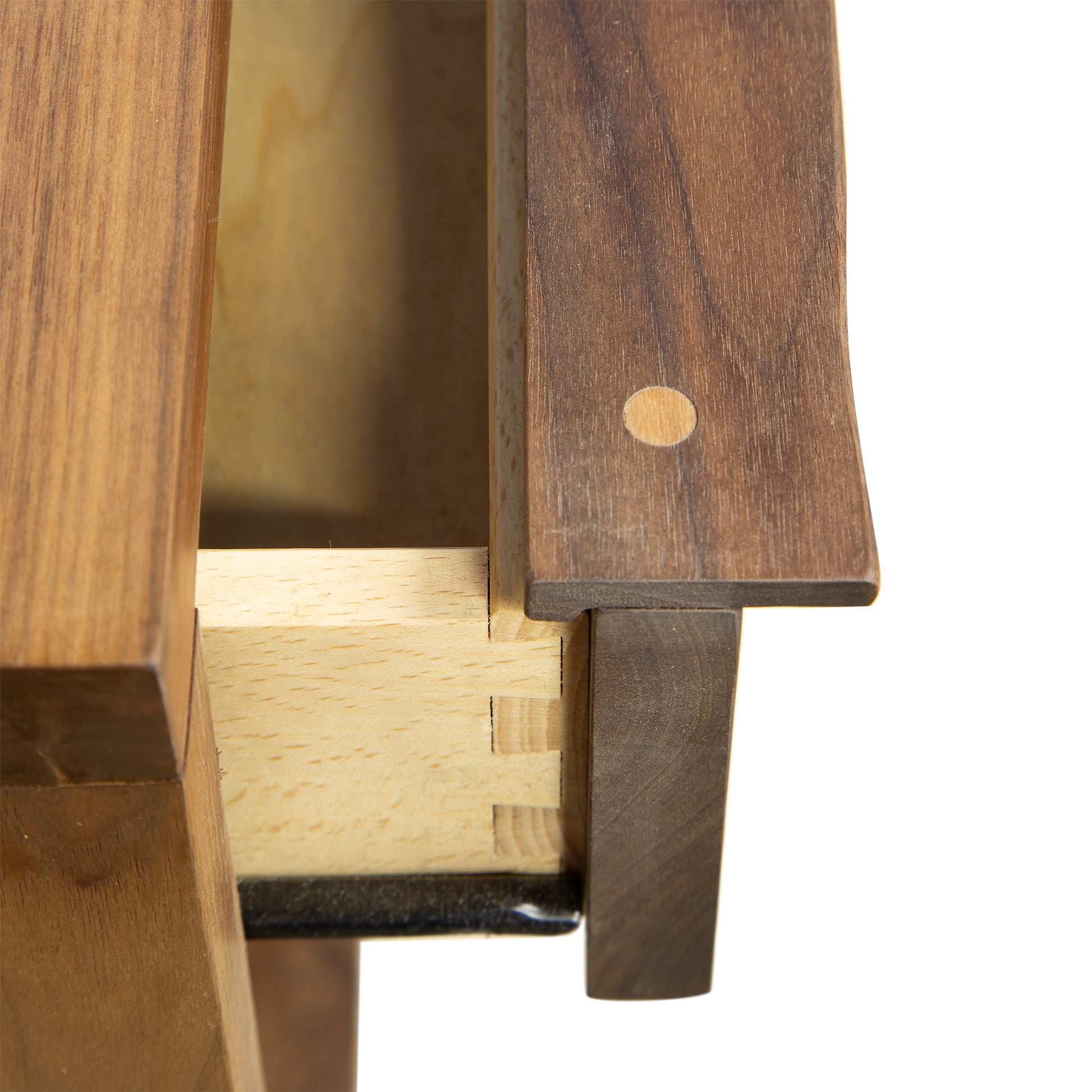 Close-up image of a wooden drawer partially opened to showcase dovetail joinery. The drawer front and side, crafted from natural maple with visible contrasting wood tones, feature a round wooden plug on the front corner. The craftsmanship exemplifies traditional woodworking techniques found in the Kipling 1-Drawer Enclosed Shelf Wide Nightstand by Vermont Furniture Designs - Walnut - Clearance.