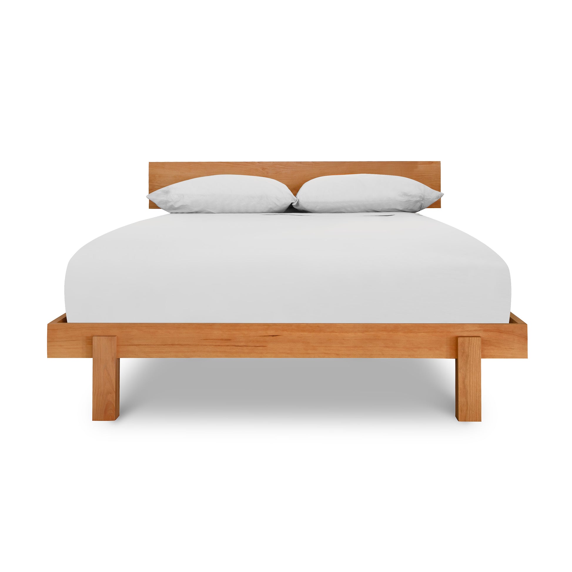 A solid wood Vermont Furniture Designs Kipling Platform Bed frame with a white mattress and two pillows against a white background.