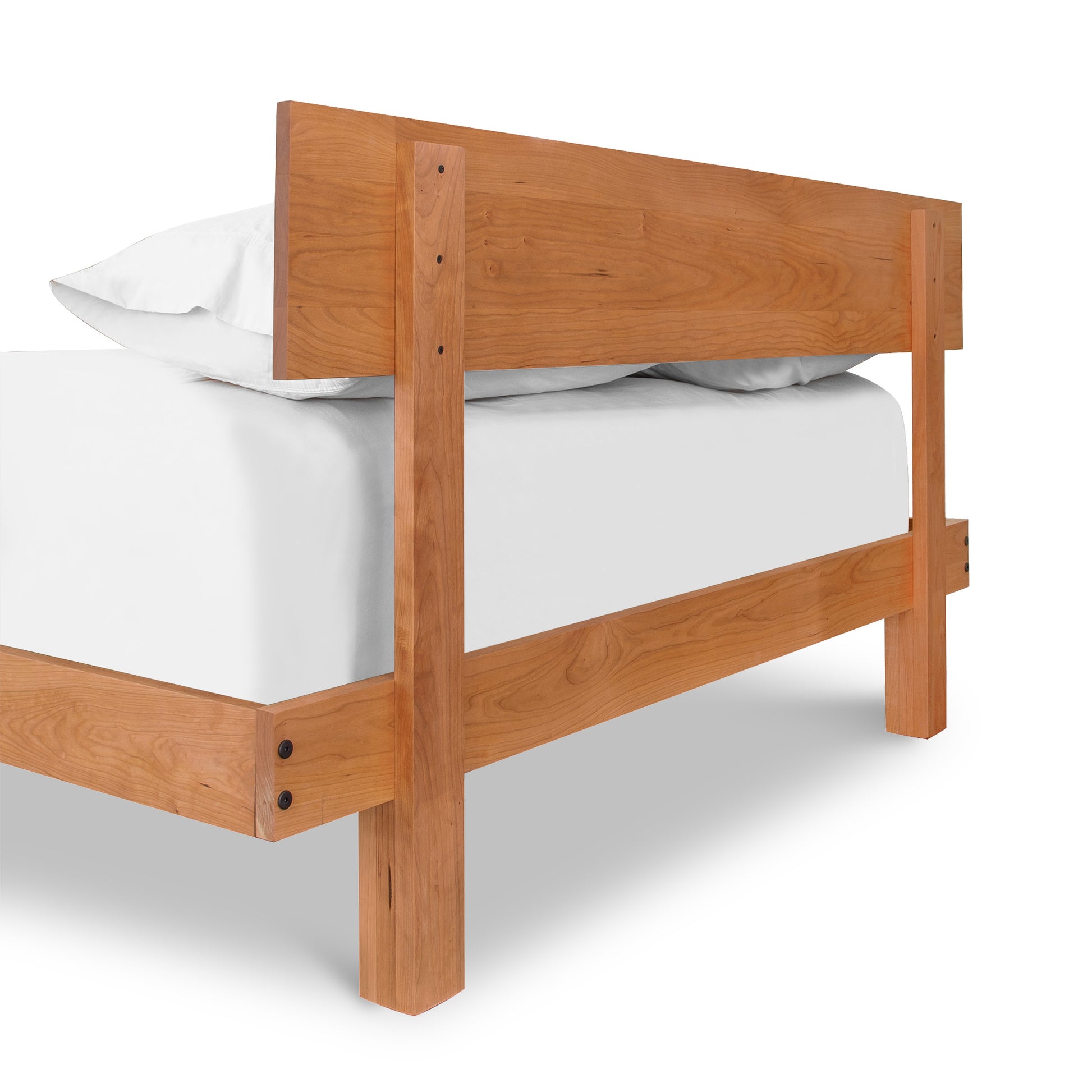 A Kipling Bed platform bed frame made of solid wood with white sheets on it. (brand name: Vermont Furniture Designs)