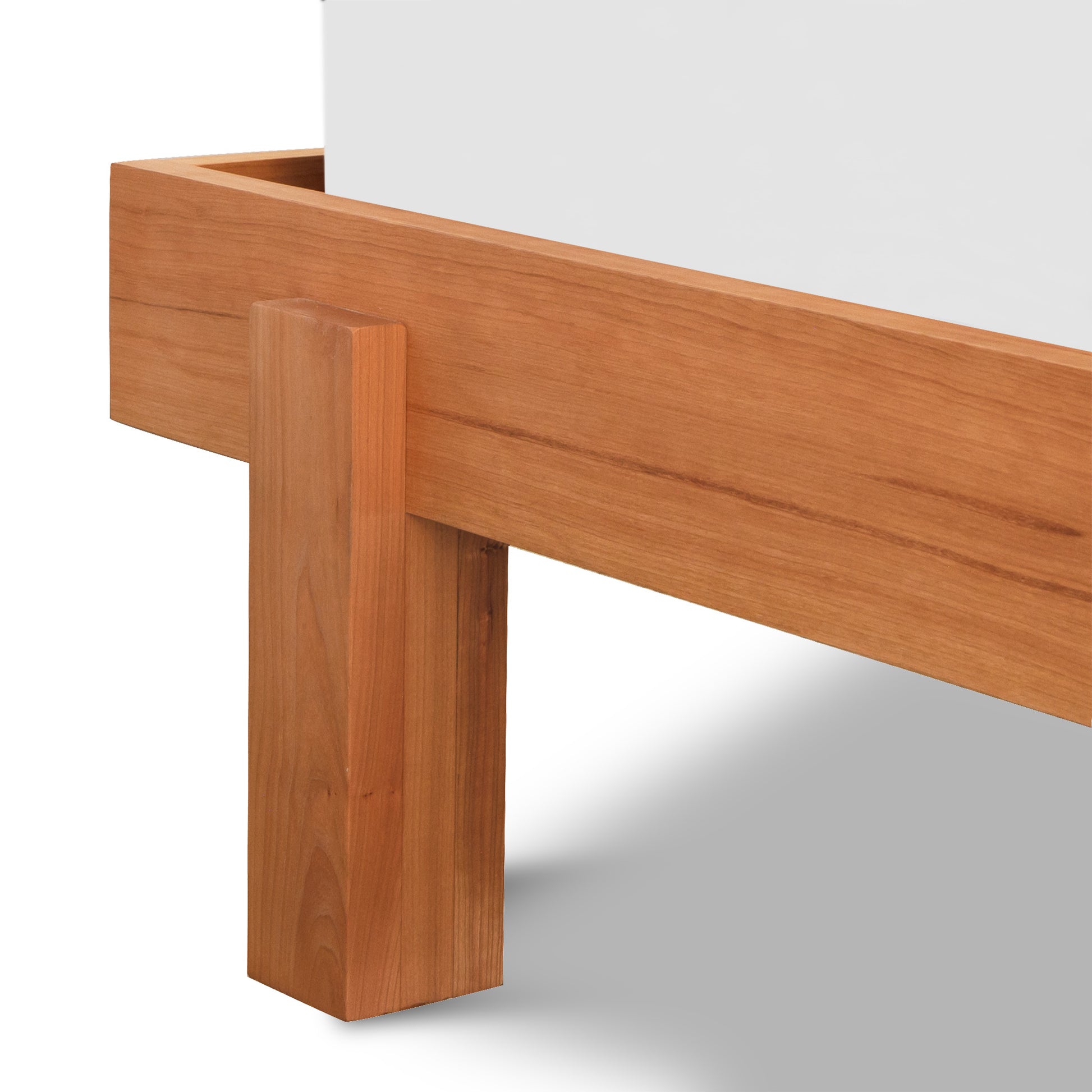 A close-up view of a Vermont Furniture Designs solid wood Kipling Bed leg connected to the tabletop, set against a white background.