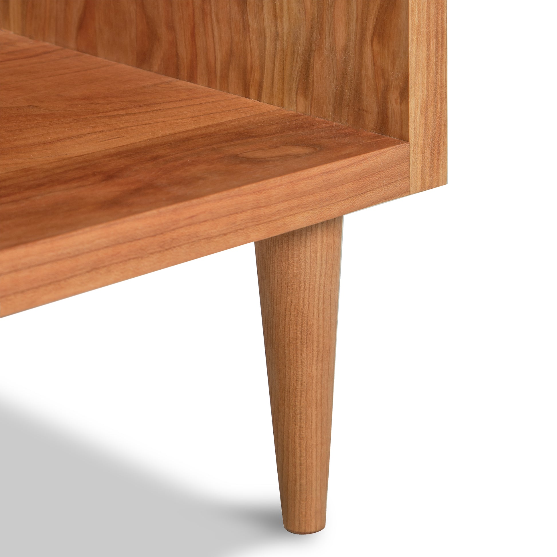 A close up of a wooden shelf from the Vermont Furniture Designs Larssen 1-Drawer Wide Nightstand with wooden legs.
