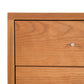 A close up of a mid-century modern wooden chest of drawers featuring the Vermont Furniture Designs Larssen 3-Drawer Nightstand.