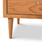 Close-up of a Vermont Furniture Designs Larssen 3-Drawer Nightstand crafted from natural hardwoods, featuring one drawer with a round knob, standing on tapered legs against a white background in a mid-century modern style.