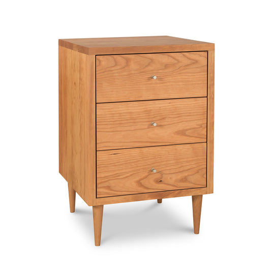 A Vermont Furniture Designs Larssen 3-Drawer Nightstand, crafted from natural hardwoods, stands on angled legs against a white background.
