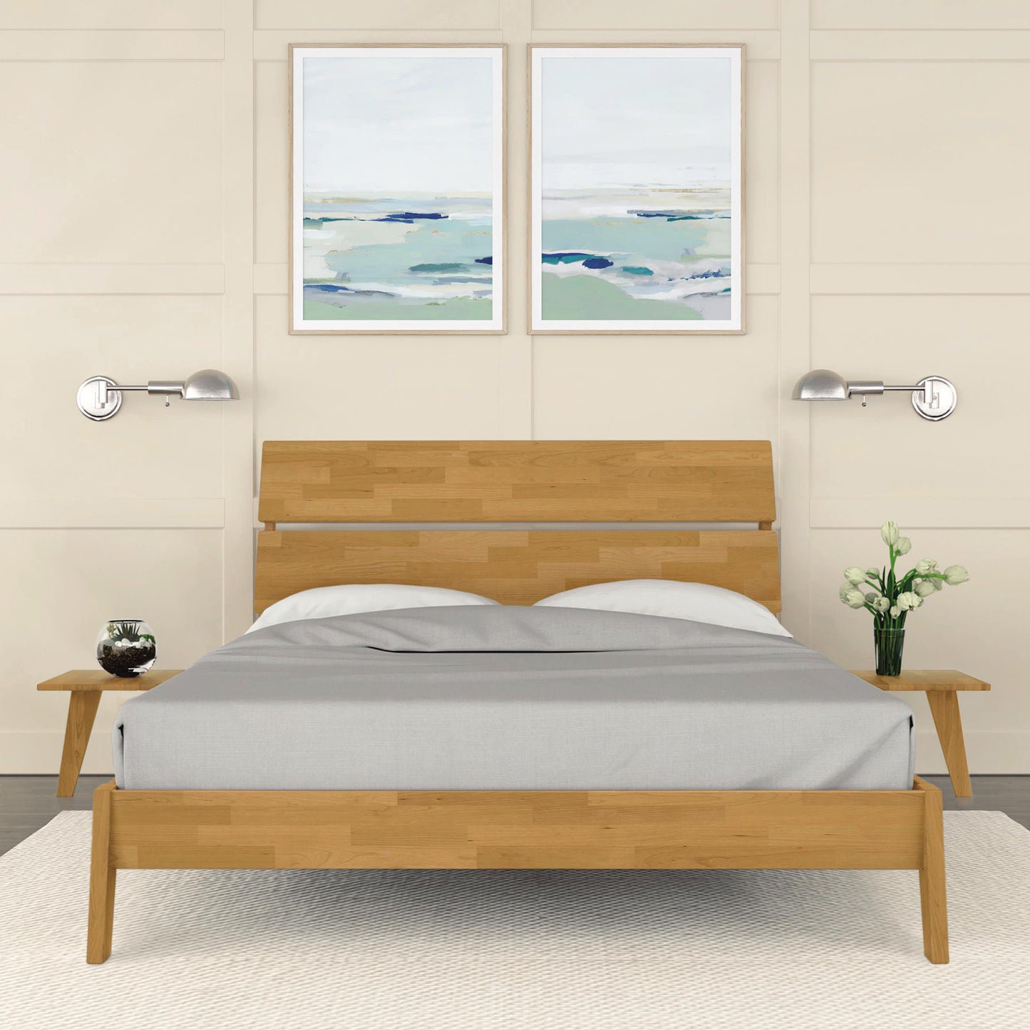 A modern bedroom features the Copeland Furniture Linn Cherry Platform Bed with gray bedding, flanked by two small wooden nightstands. Each nightstand holds a candle and a vase with flowers. Above the bed, two framed abstract paintings in blue and green hues complete the look. Sustainable furniture ensures an eco-friendly touch.