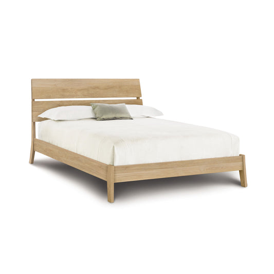A modern Linn oak platform bed frame with a slatted headboard and a white mattress with bedding from Copeland Furniture.