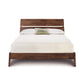 Copeland Linn Platform Bed in walnut, queen size with a slatted headboard, made in America. Premium craftsmanship showcased; bedding is white with a green pillow.