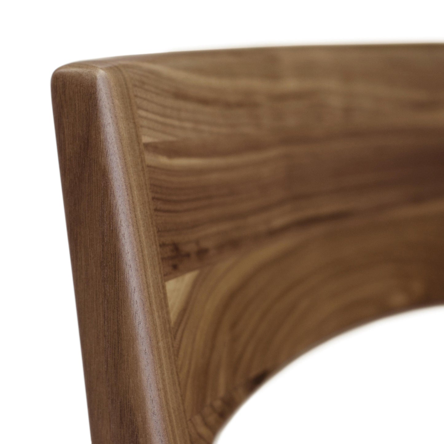 Close-up of a smoothly curved walnut chair arm from the Copeland Furniture Lisse Dining Chair, with visible wood grain detail.