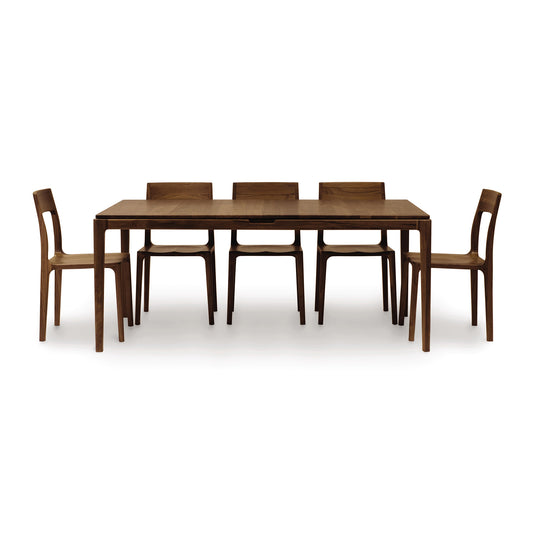A sculptural minimalist design Lisse Extension dining table by Copeland Furniture with six chairs, featuring sustainable solid walnut construction for an organic feel.