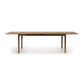 An eco-friendly Lisse Extension Dining Table, crafted from solid walnut construction, with thin legs on a white background by Copeland Furniture.