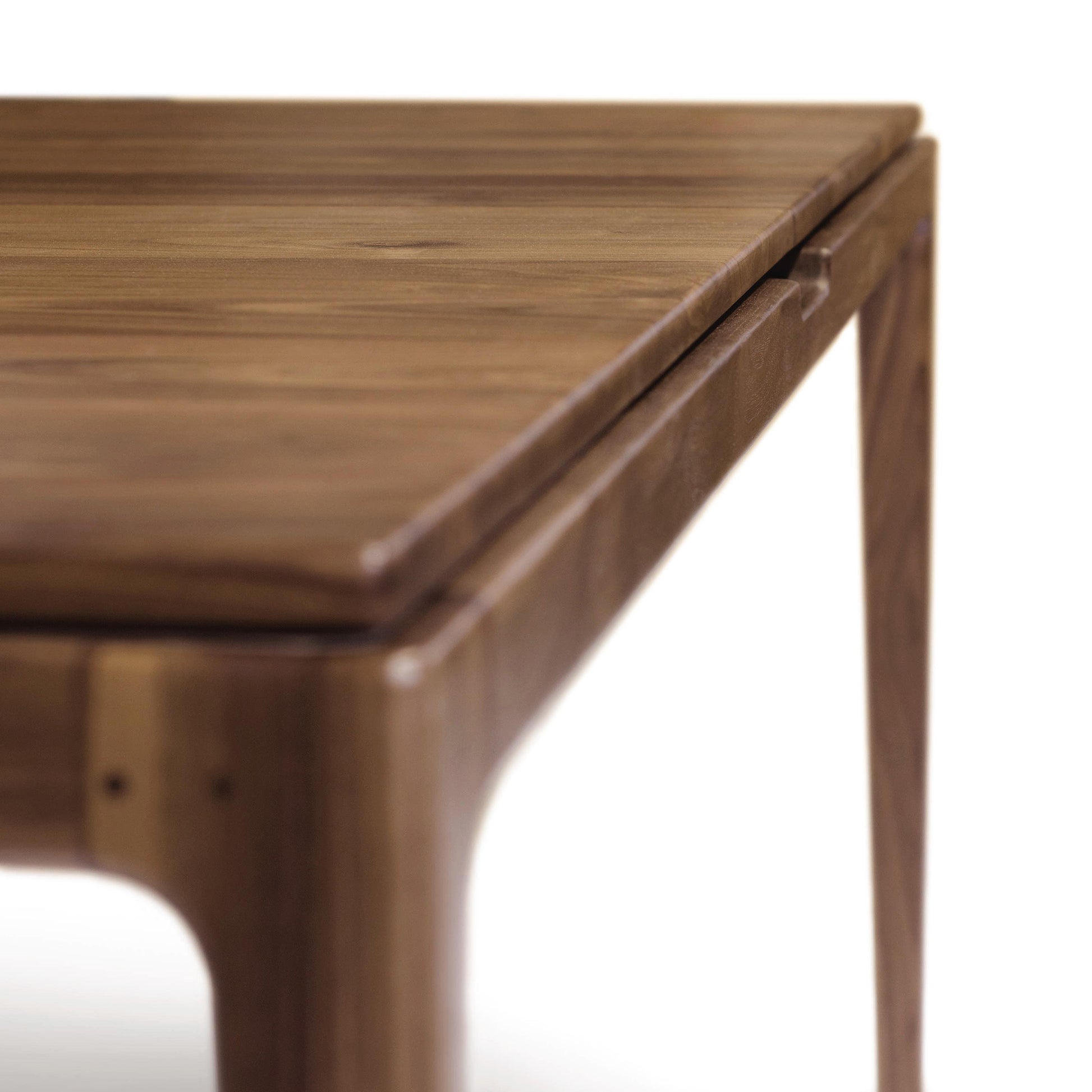 Close-up of a Copeland Furniture Lisse Extension Dining Table corner showing the grain and texture of the wood with a blurred background.