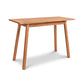 A Manchester Compact Desk in natural cherry wood finish from Vermont Woods Studios, featuring four angled legs. This American-made, solid wood desk showcases a minimalist, clean design with a flat surface and smooth edges. The slightly tapered legs provide sturdy support and cast a soft shadow on the white background. Perfect for small spaces, this cherry wood desk adds elegance to any home or office.