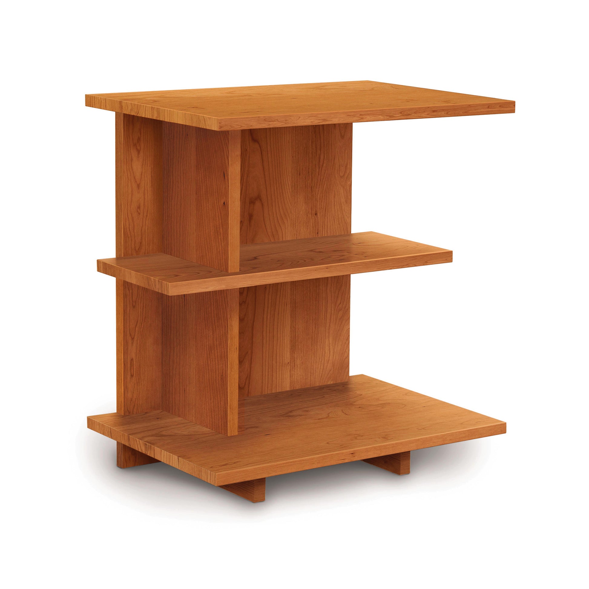 The Mansfield Open Shelf Nightstand by Copeland Furniture features a modern, minimalist design with three rectangular shelves arranged in a staggered layout. Made of light brown wood, the top shelf is the smallest, the middle shelf is slightly larger, and the bottom shelf is the largest.