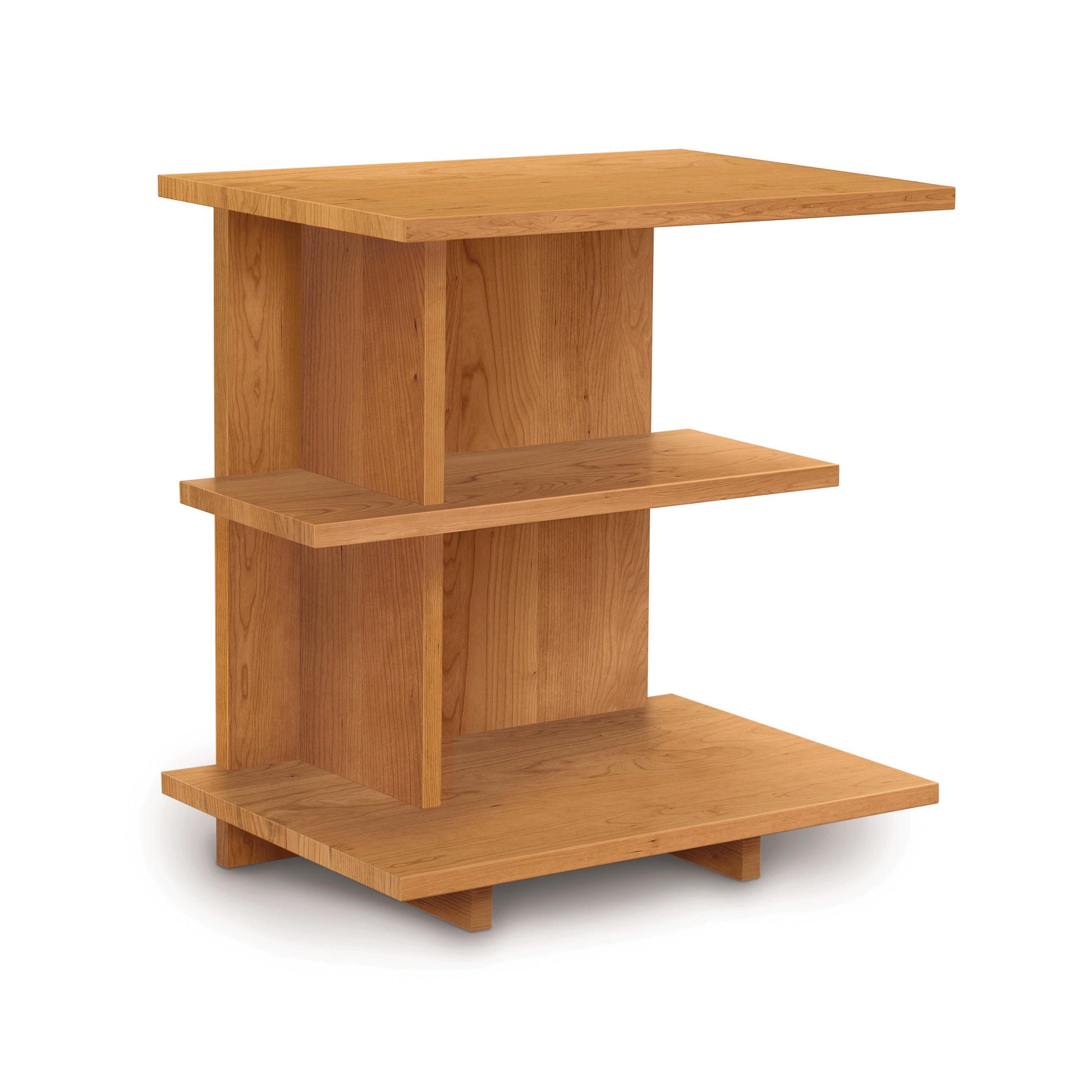 The Mansfield Open Shelf Nightstand from Copeland Furniture is a small, light brown wooden side table featuring three-tiered rectangular shelves of varying sizes, supported by vertical wooden panels. This piece boasts a simple, modern design and stands on four small feet, making it perfect for pairing with your cherry bedroom furniture.