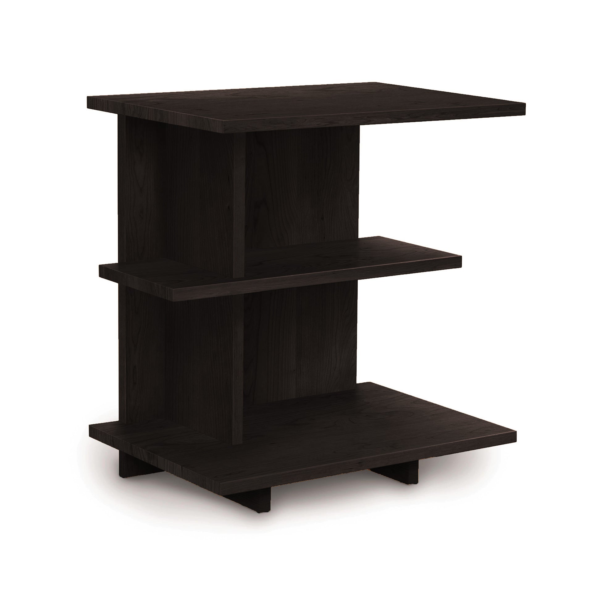 The Mansfield Open Shelf Nightstand from Copeland Furniture is a small, black wooden side table featuring three-tiered shelves. Its modern design includes a Z-shaped frame supporting the horizontal platforms and stands on four short, rectangular legs. The nightstand boasts a minimalist aesthetic similar to cherry bedroom furniture.