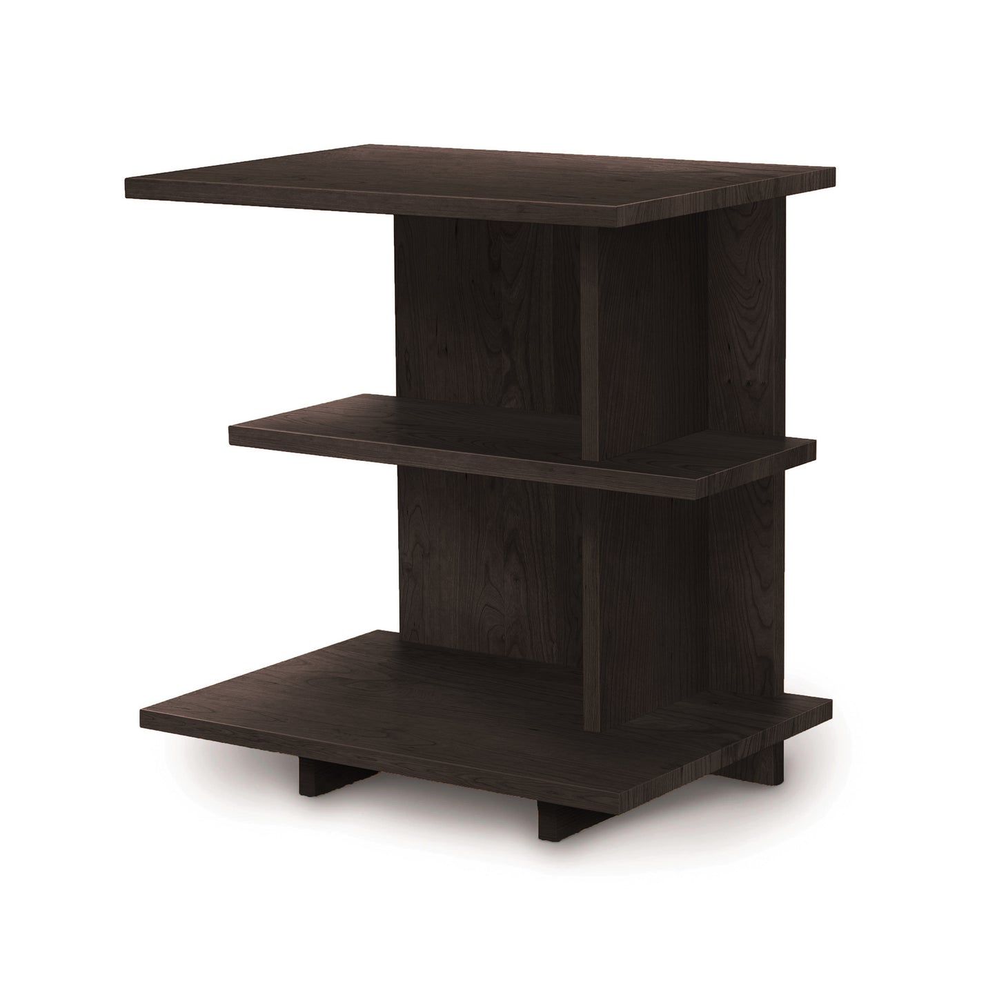 Introducing the Mansfield Open Shelf Nightstand by Copeland Furniture. This charming cherry bedroom furniture piece boasts a small dark wood shelf unit with two flat surfaces and a vertical back panel. Its open, asymmetrical design features shelves extending outward at varying levels, making it the perfect match for your cherry nightstand.