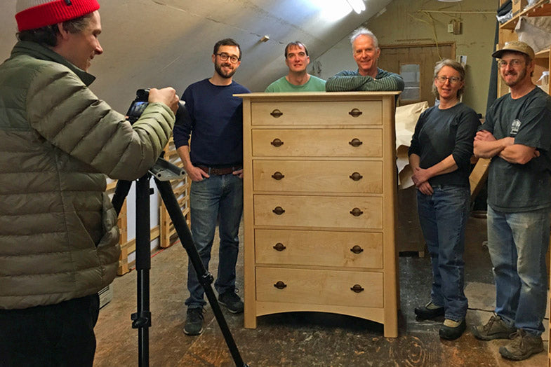 A group of people standing in front of a dresser.