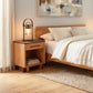 Vermont Furniture Designs Modern American Nightstand beside a bed, highlighting quality craftsmanship and elegant wooden construction.