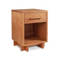The Modern American 1-Drawer Enclosed Shelf Nightstand - 26" High - Floor Model by Vermont Furniture Designs boasts a light brown natural cherry finish. Standing on four small legs, it features a drawer with a horizontal handle and an enclosed storage space below. Crafted by Vermont craftsmen, its minimalist design is highlighted by clean lines and the natural wood texture.