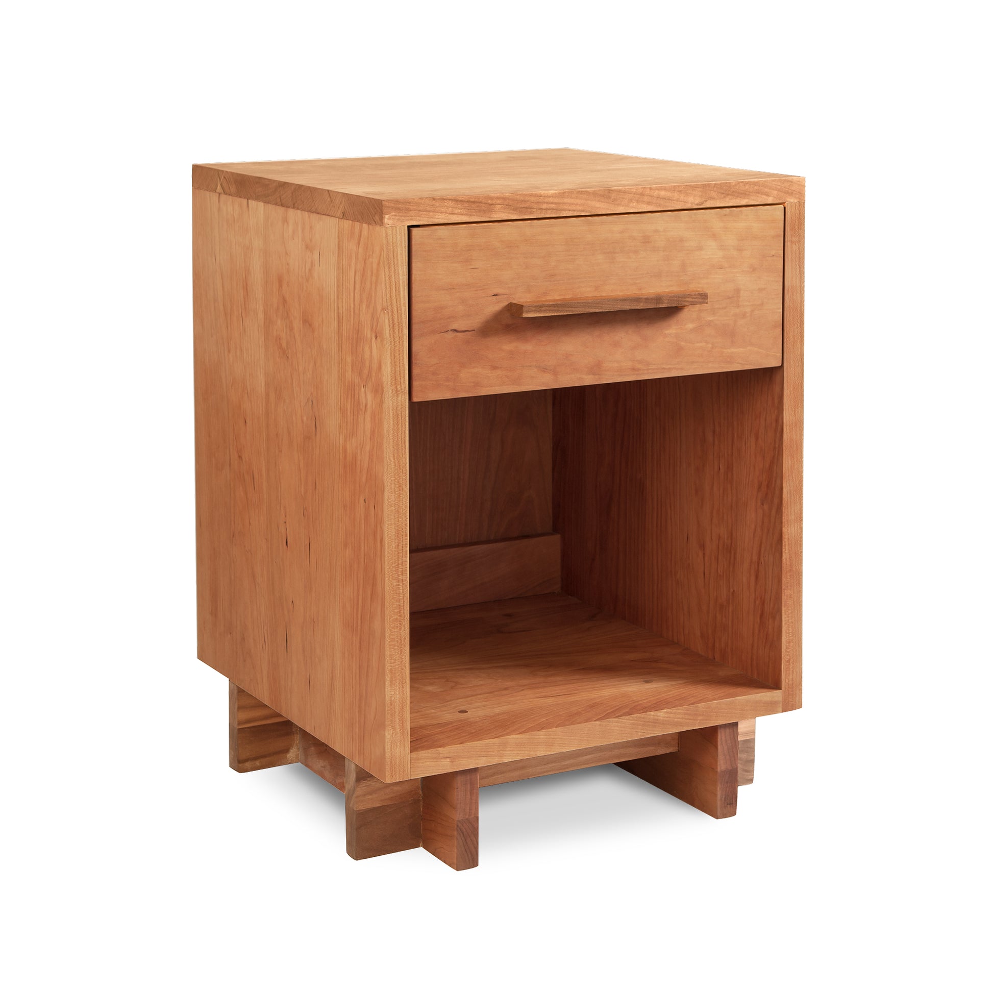 The Modern American 1-Drawer Enclosed Shelf Nightstand - 26" High - Floor Model by Vermont Furniture Designs boasts a light brown natural cherry finish. Standing on four small legs, it features a drawer with a horizontal handle and an enclosed storage space below. Crafted by Vermont craftsmen, its minimalist design is highlighted by clean lines and the natural wood texture.