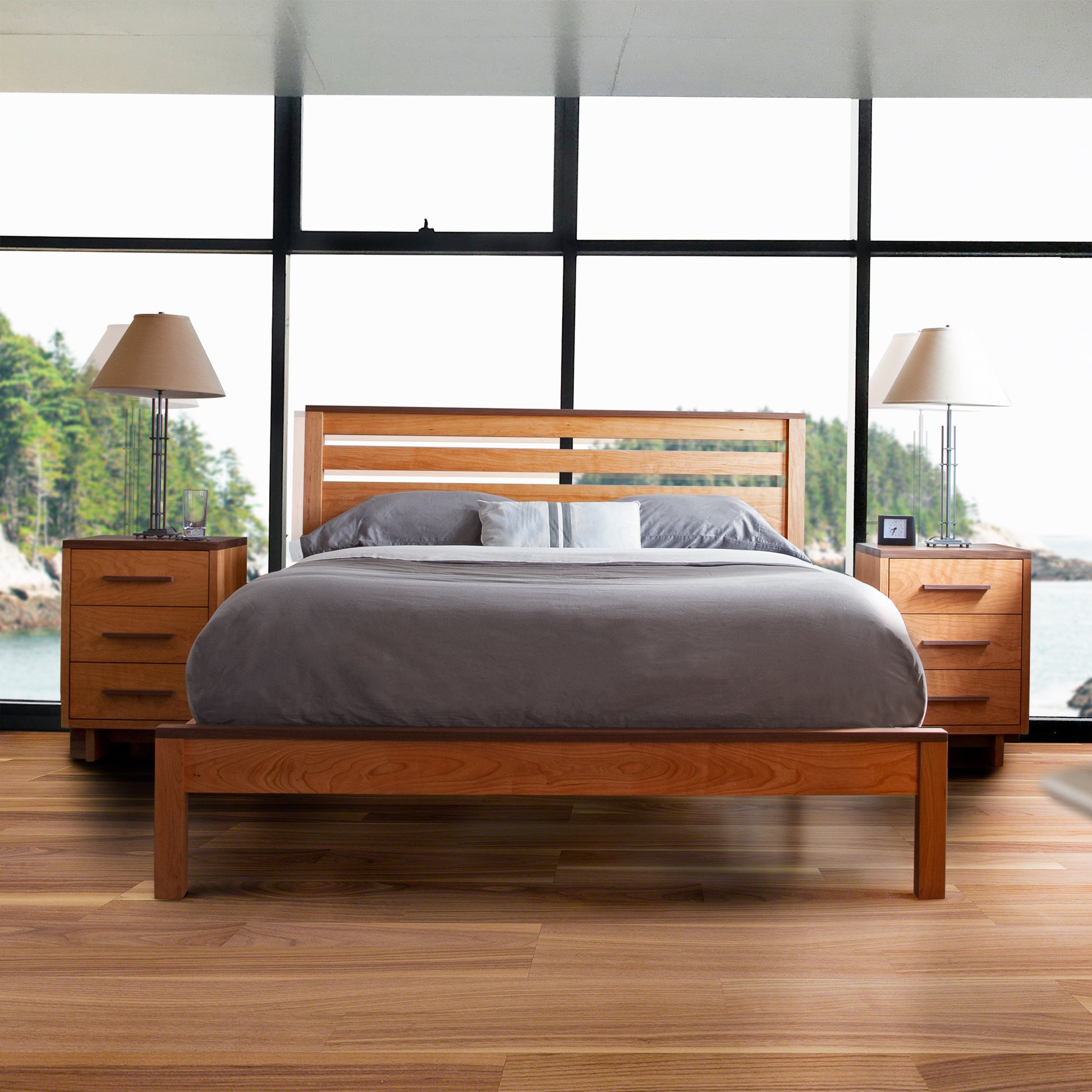 A wooden bed with a gray comforter flanked by two Vermont Furniture Designs Modern American 3-Drawer Nightstands.