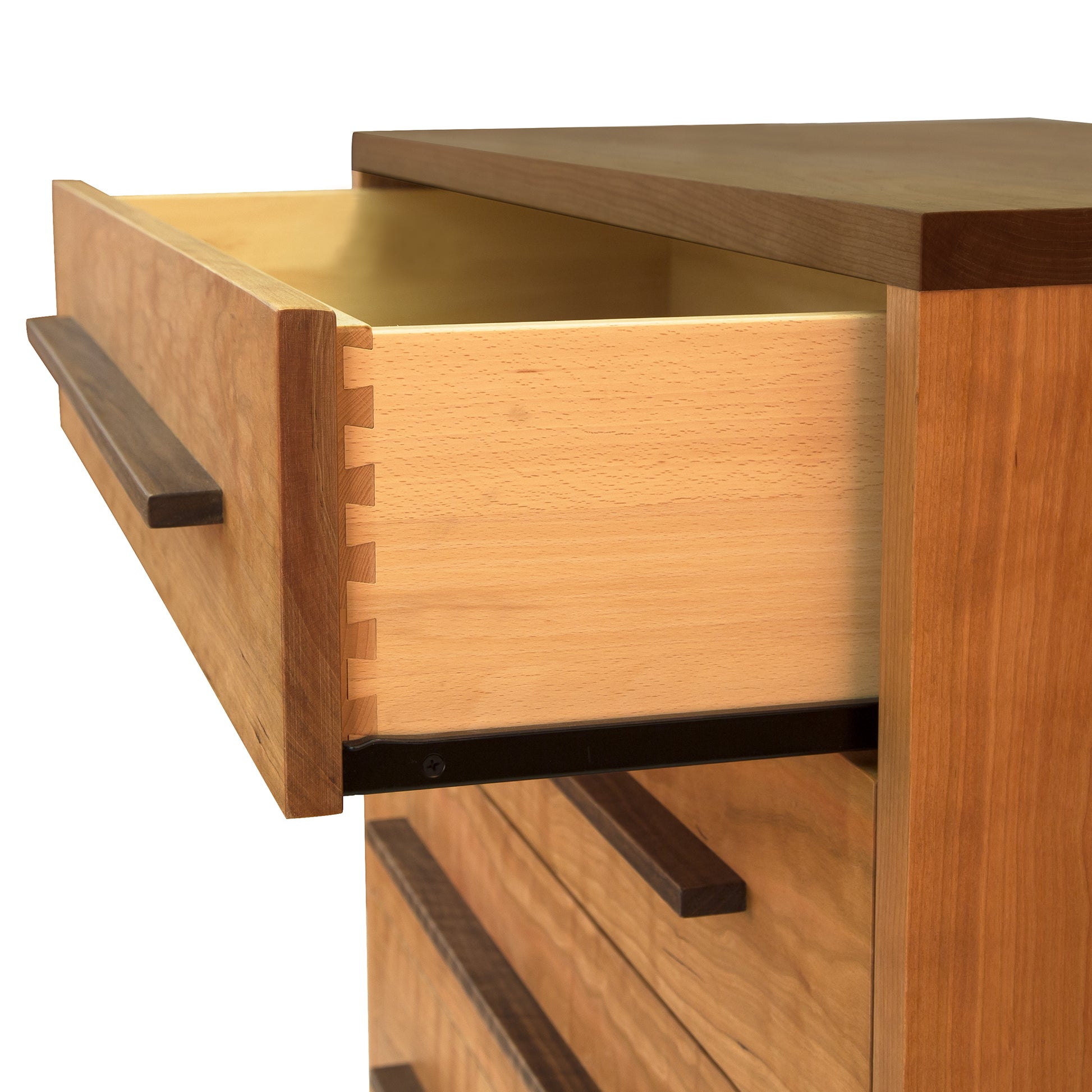 Close-up view of an open drawer in a Modern American 5-Drawer Chest from Vermont Furniture Designs showing detailed dovetail joints and an eco-friendly oil finish. The chest's rich grain patterns and robust construction are prominently displayed.