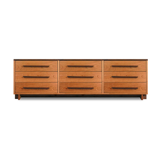 A natural cherry wooden Modern American 9-Drawer Dresser with elongated handles against a plain background. (Brand Name: Vermont Furniture Designs)