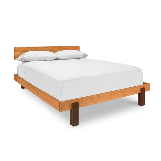 A Vermont Furniture Designs Modern American Platform Bed crafted from solid hardwoods, with a white mattress and two pillows, isolated on a white background.