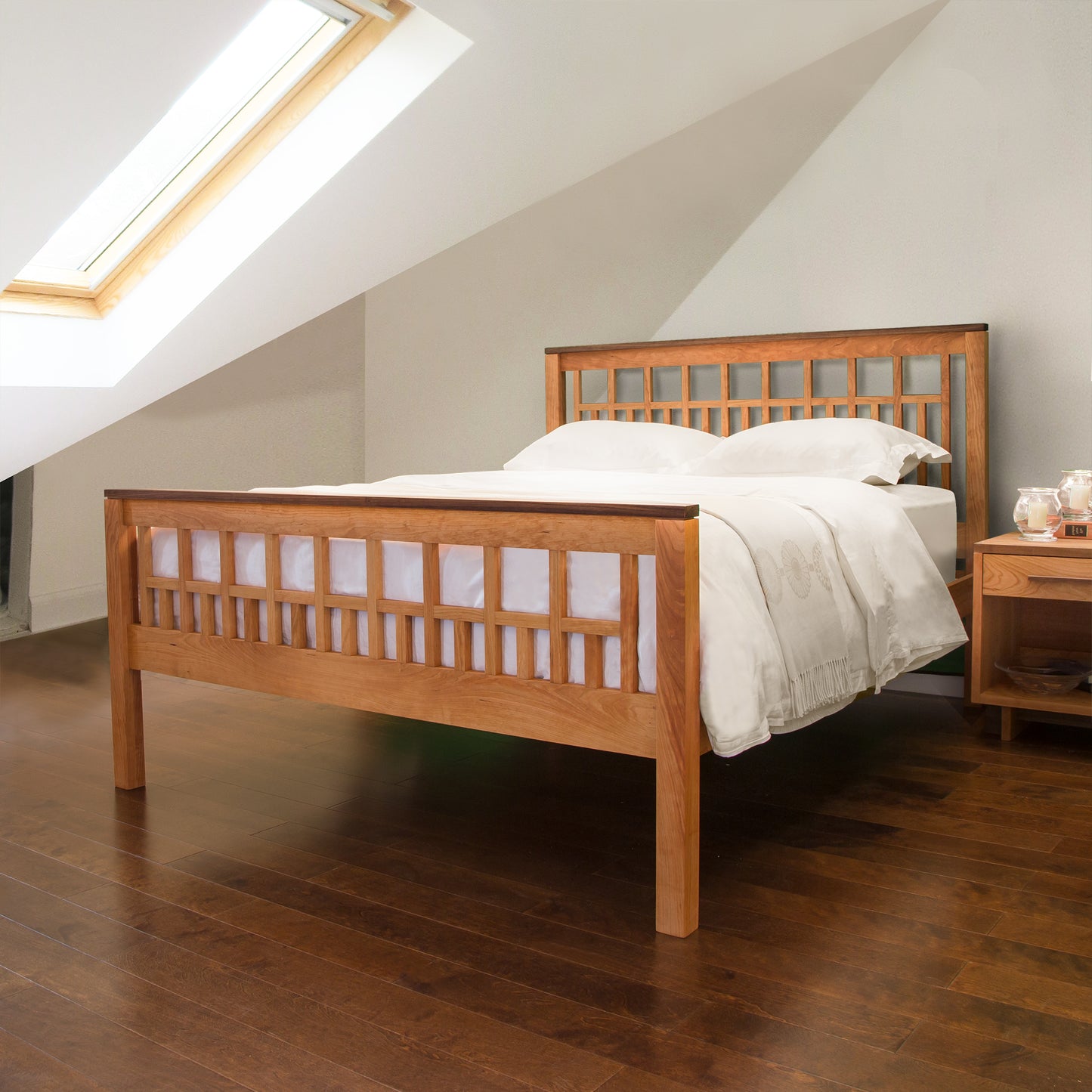 A solid hardwoods Vermont Furniture Designs Modern American Trellis Bed frame with white bedding under a sloped ceiling with a skylight in a modern attic bedroom.