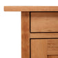 A close up of a wooden cabinet with the Vermont Furniture Designs Modern Craftsman 1-Drawer Nightstand with Door design.