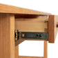 An open drawer of a Vermont Furniture Designs Modern Craftsman 2-Drawer Console Table, made from sustainably sourced North American hardwoods, showing the metal slide mechanism.