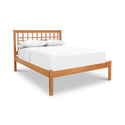 Solid wood Modern Craftsman Low Footboard Bed by Vermont Furniture Designs, featuring a grid-style headboard, white mattress and pillows. Crafted from high-quality American cherry wood. Contemporary and minimalist furniture design against a plain white background.
