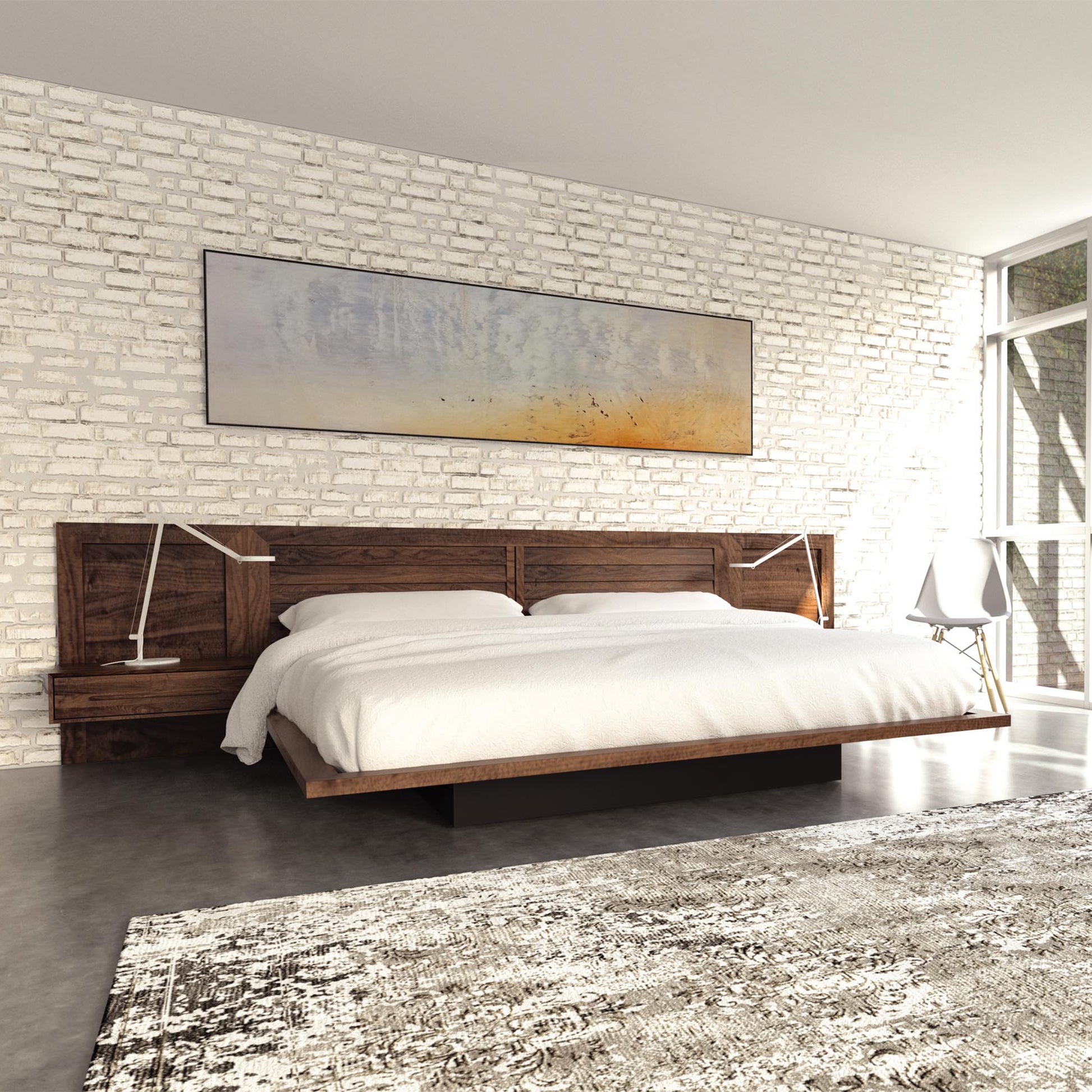 A minimalist bedroom features a Vermont handmade Copeland Furniture Moduluxe Platform Bed with Clapboard Headboard - 35" Series, dressed in white bedding. Two modern lamps rest on matching wooden nightstands. A large abstract painting hangs on a white brick wall. Natural light enters through large windows, illuminating a textured rug on the floor.